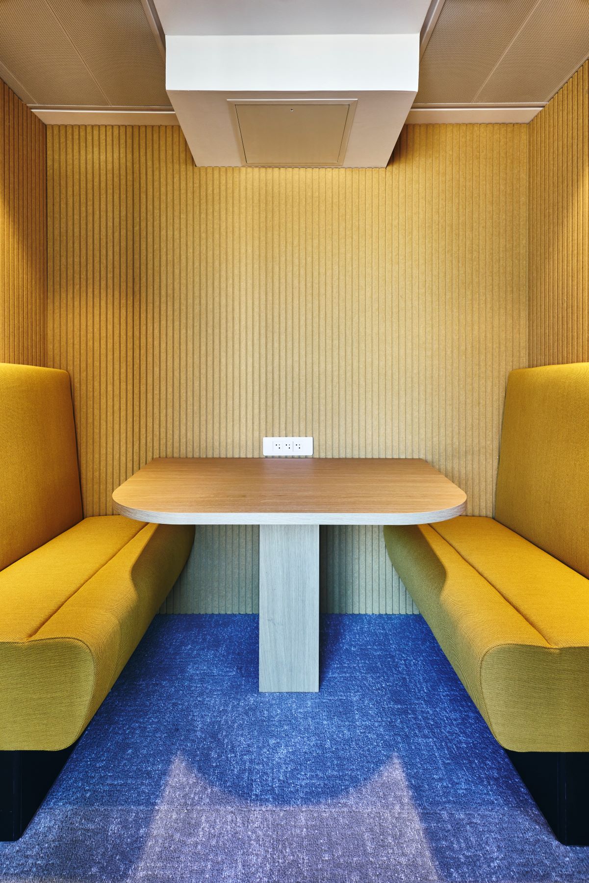 Aménagement d'un box insonorisé chez CCR, avec table sur mesure, panneaux acoustiques, banquette sur mesure.