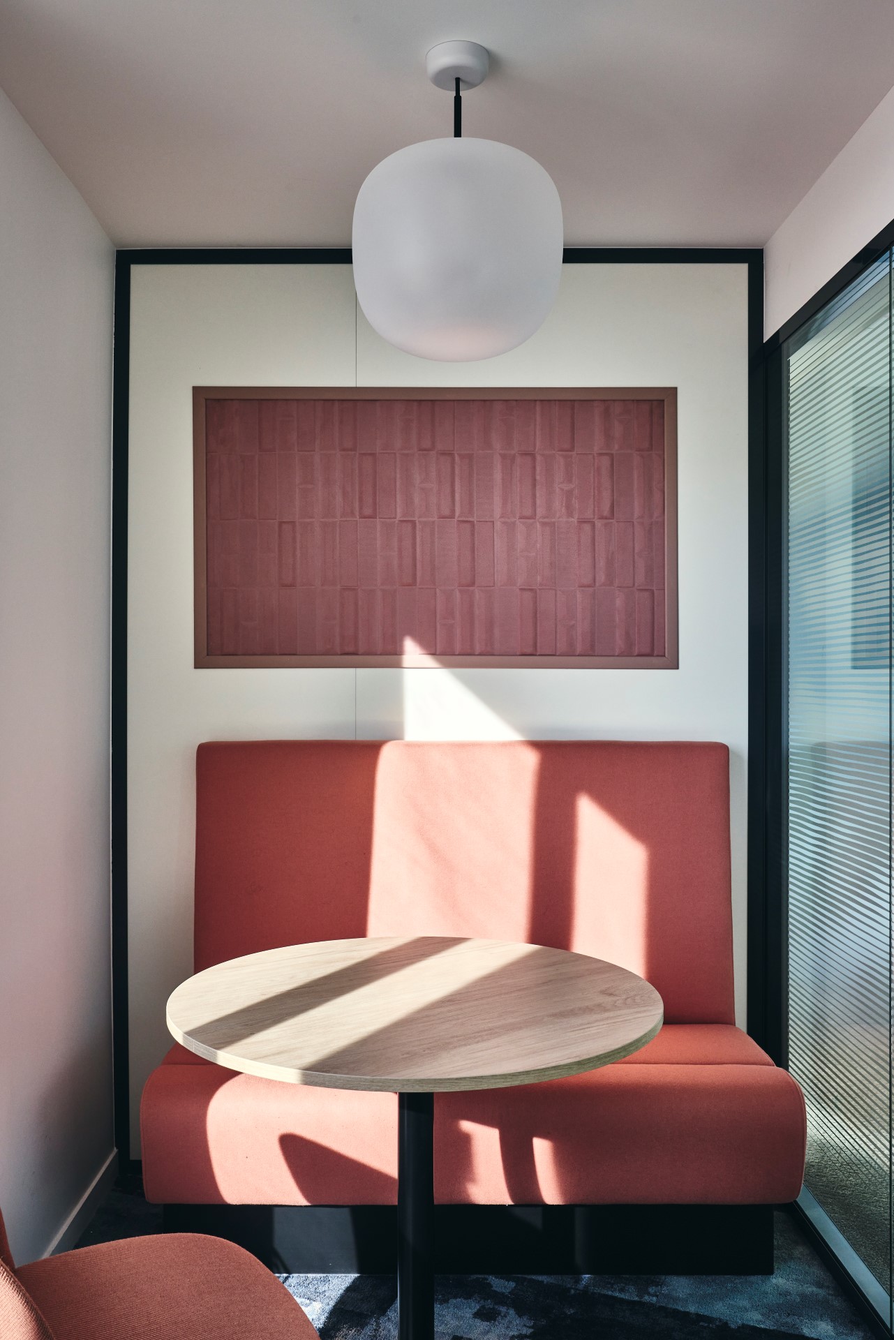 Aménagement d'un box 2 personnes chez CCR, avec banquette sur mesure, panneau acoustique, suspension luminaire globe.