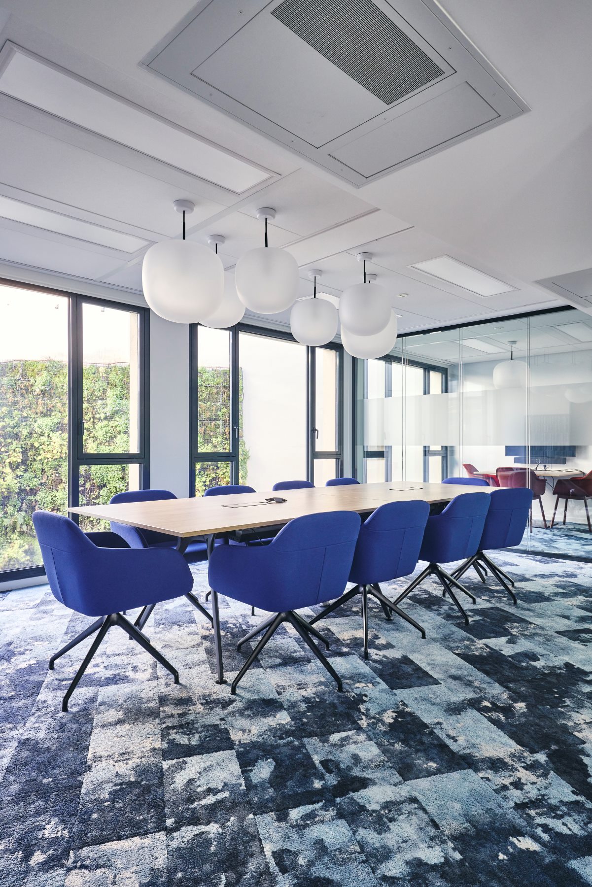 Aménagement d'une salle de réunion 10 personnes chez CCR, avec suspension luminaire globe, moquette graphique déco, fauteuil confort et cloison double vitrage acoustique.