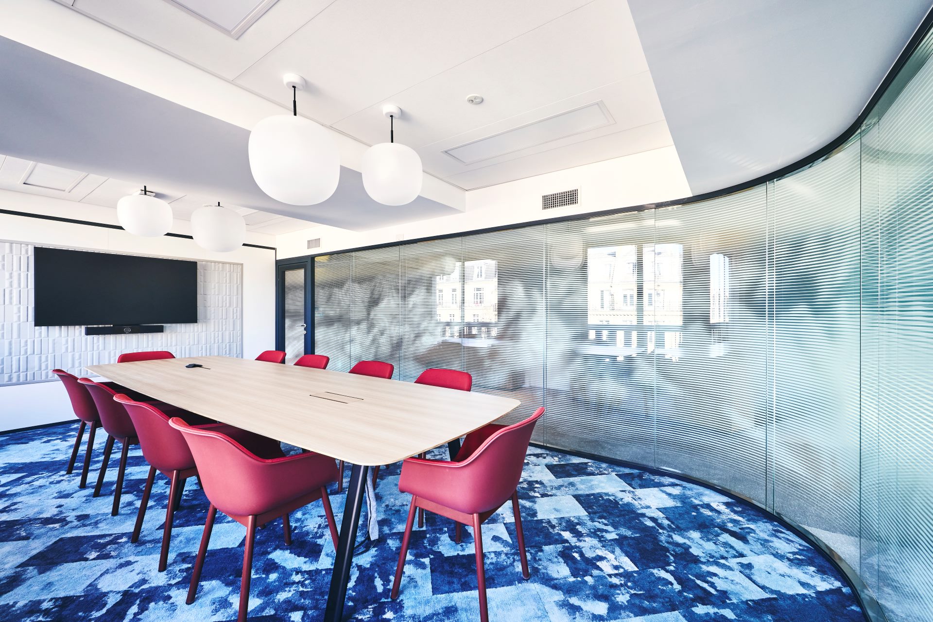 Aménagement d'une salle de réunion chez CCR, avec cloison double vitrage acoustique et courbe, vitrophanie, table de réunion en bois 10 personnes, fauteuils de réunion, suspension luminaire globe et moquette déco