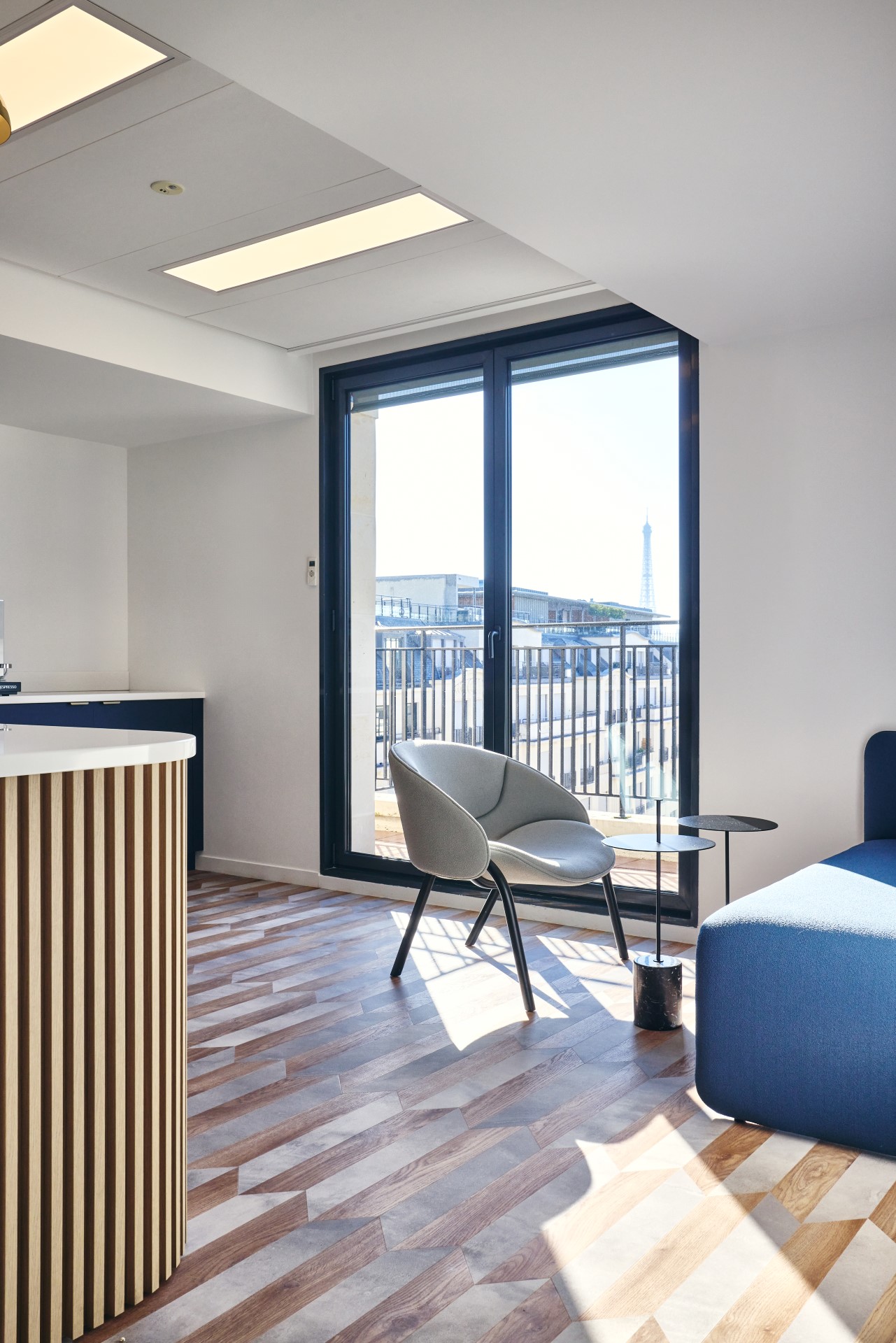 Création d'un espace détente chez CCR, avec fauteuil confort et design, PVC au sol effet bi-matière métal et bois, vue sur la tour Eiffel